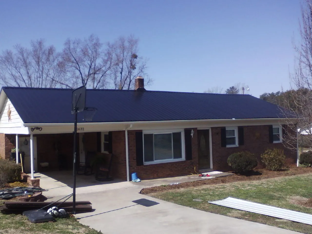 Finished dark blue metal roof on a brick ranch with a carport in Deadwood