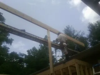 Carpenter setting a ridge beam over a new addition frame — Ice Dam Removal by Roofing Brothers in Deadwood