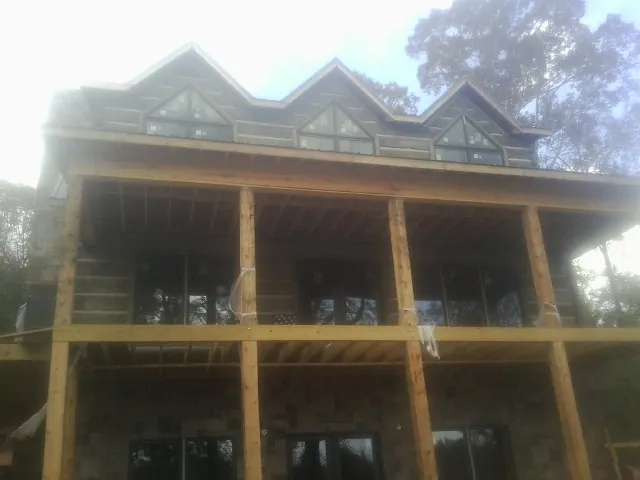 Dormers and porch framing on a large log home under construction — Roof Coating work by our crew in Deadwood